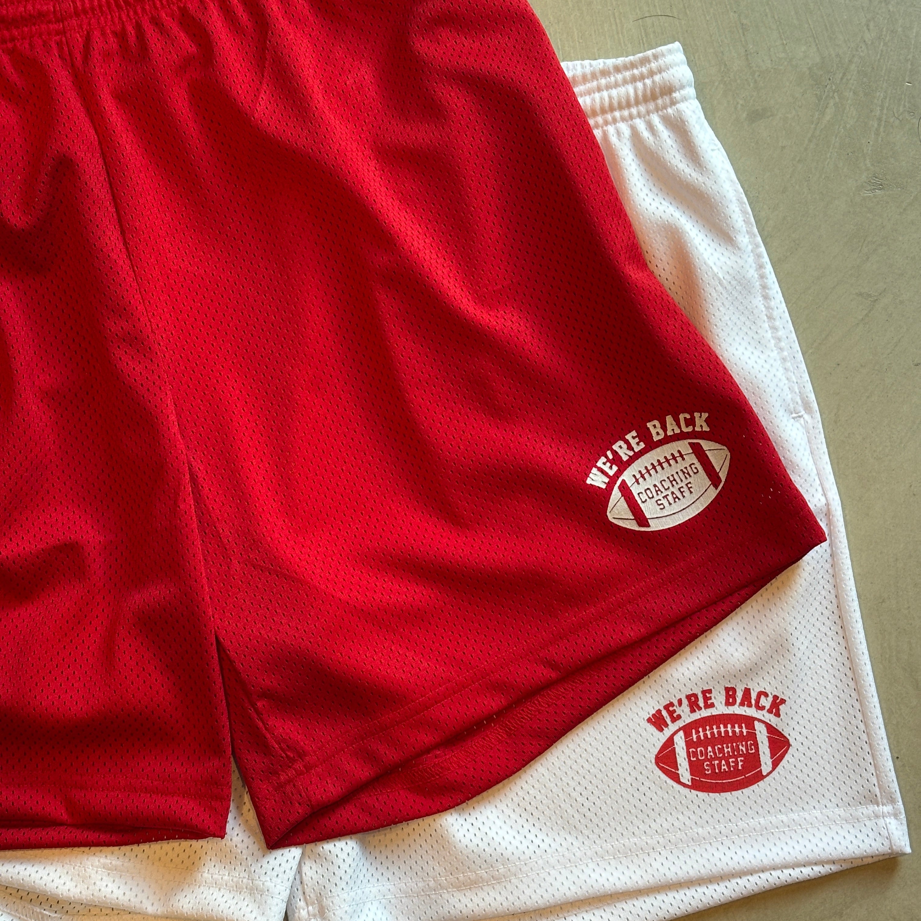 Red athletic shorts with a logo on a beige surface