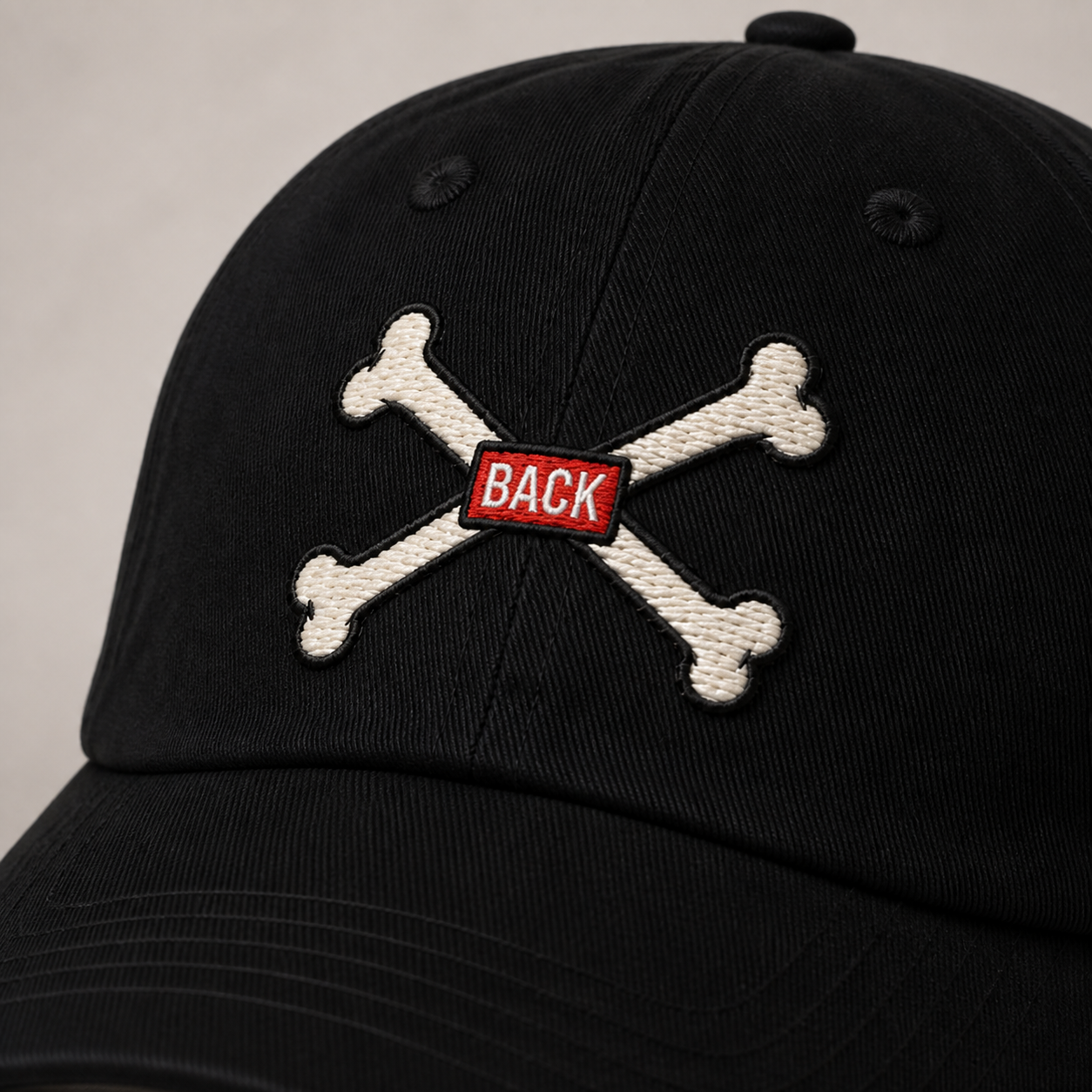 Close-up of black Bones Dad Hat crossed-bones embroidery and red BACK tab