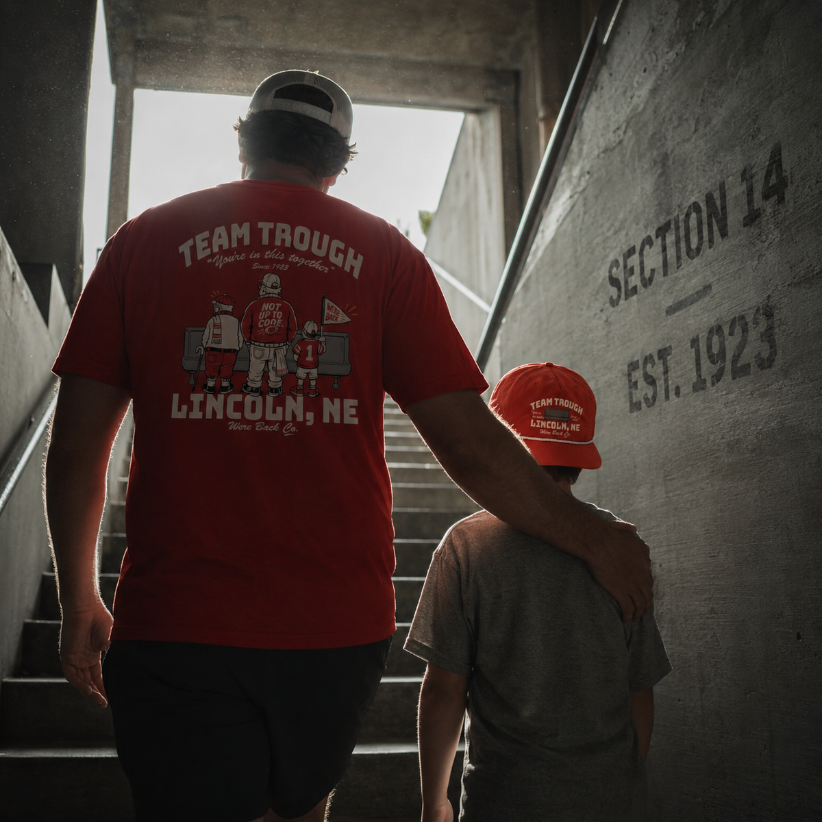 Father and son in Team Trough gear walking up the stadium tunnel