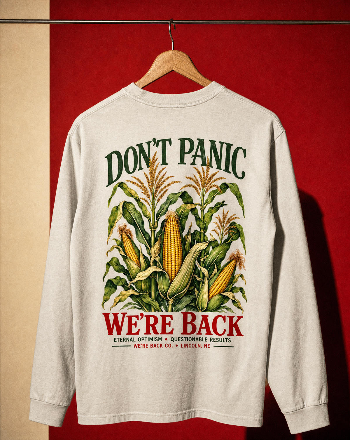 Back of the faded bone Don't Panic Long Sleeve on a hanger against a red wall.