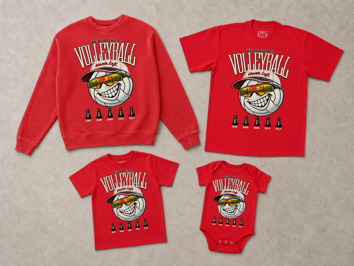 A coordinated family apparel set laid flat on a light beige textured background, including a red crewneck sweatshirt, a red short-sleeve T-shirt, a red short-sleeve T-shirt, and a red one-piece baby garment. Each piece features a large volleyball graphic with sunglasses, the word VOLLEYBALL, and small bottle silhouettes underneath.