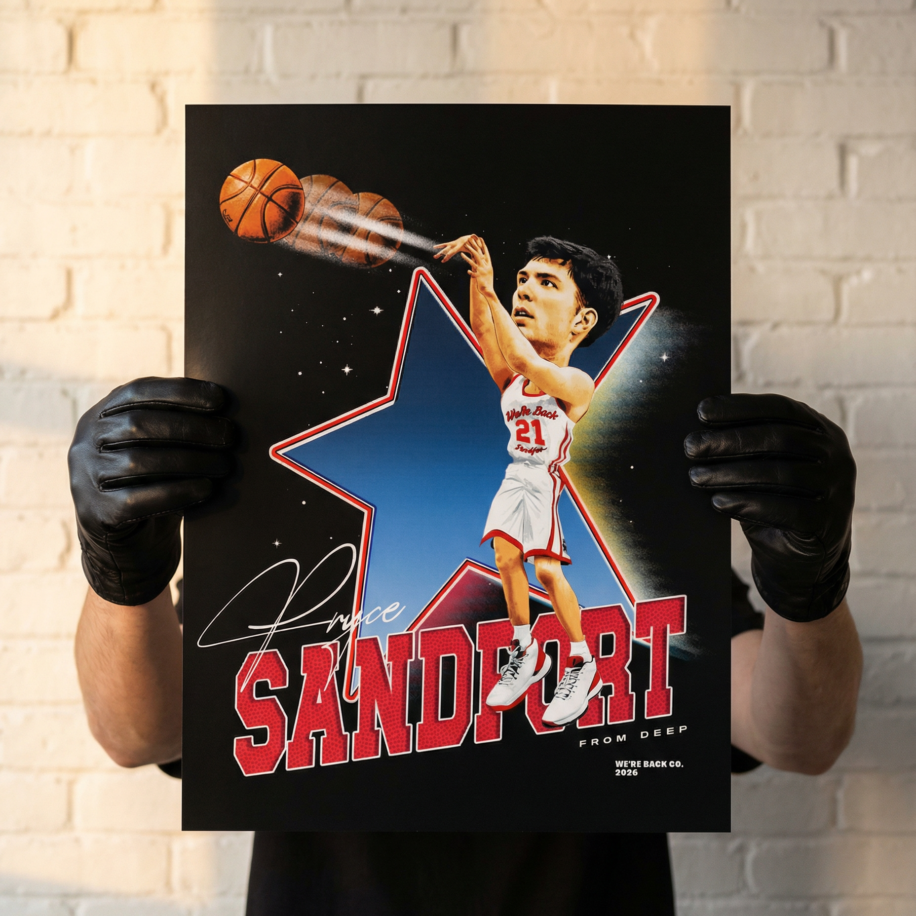 Person holding a poster of a basketball player with a star and 'Sandfort' text against a brick wall.