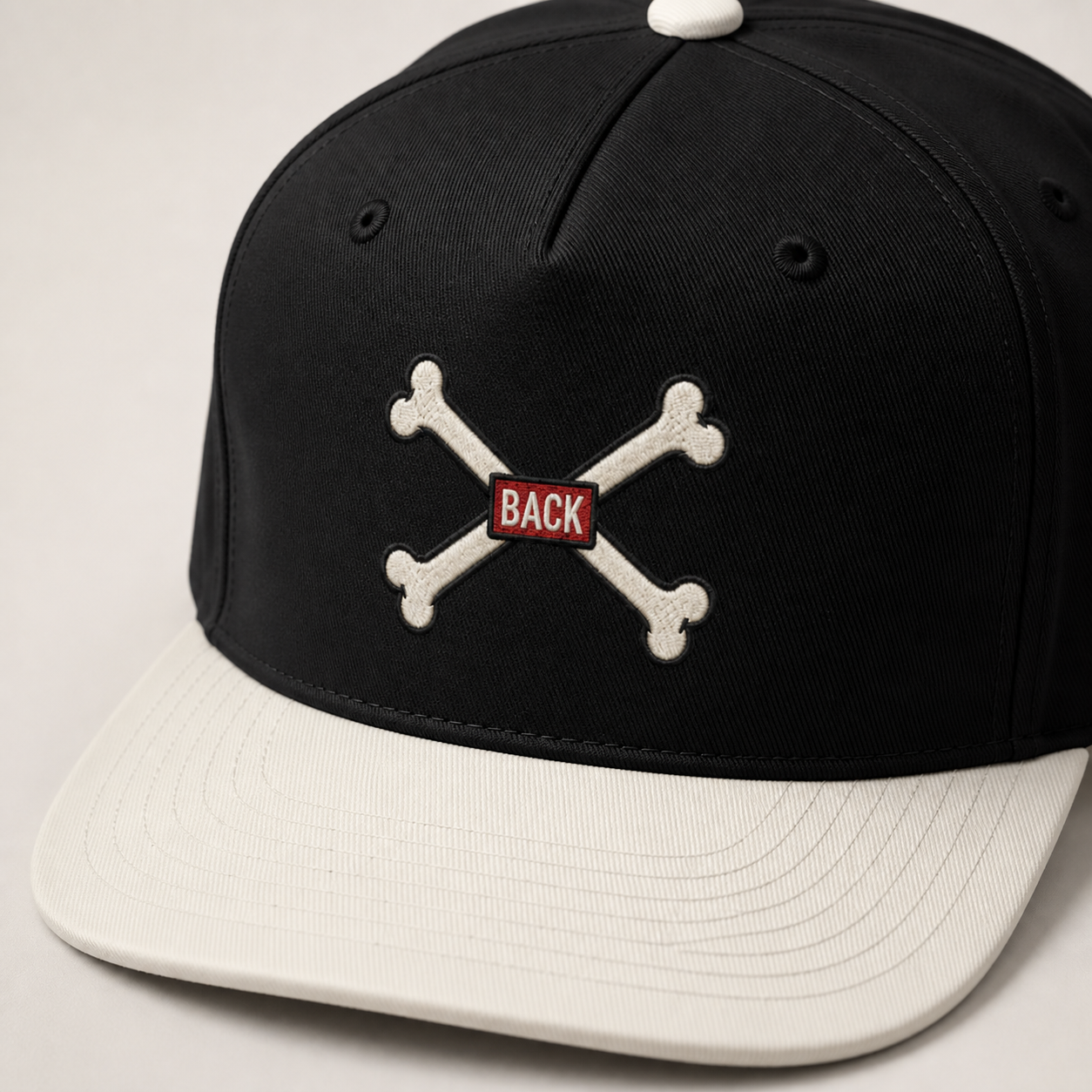 Close-up of black-and-natural Bones Two-Tone Hat with crossed-bones DTF print and embroidery-style finish