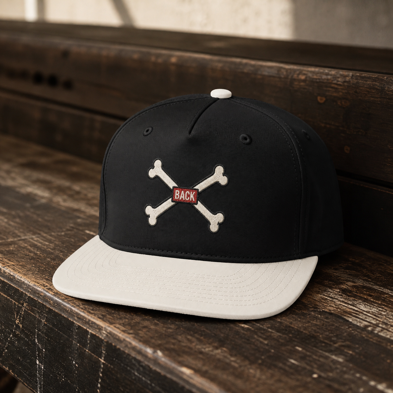 Black-and-natural Bones Two-Tone Hat lifestyle photo with crossed-bones DTF print and red BACK tab