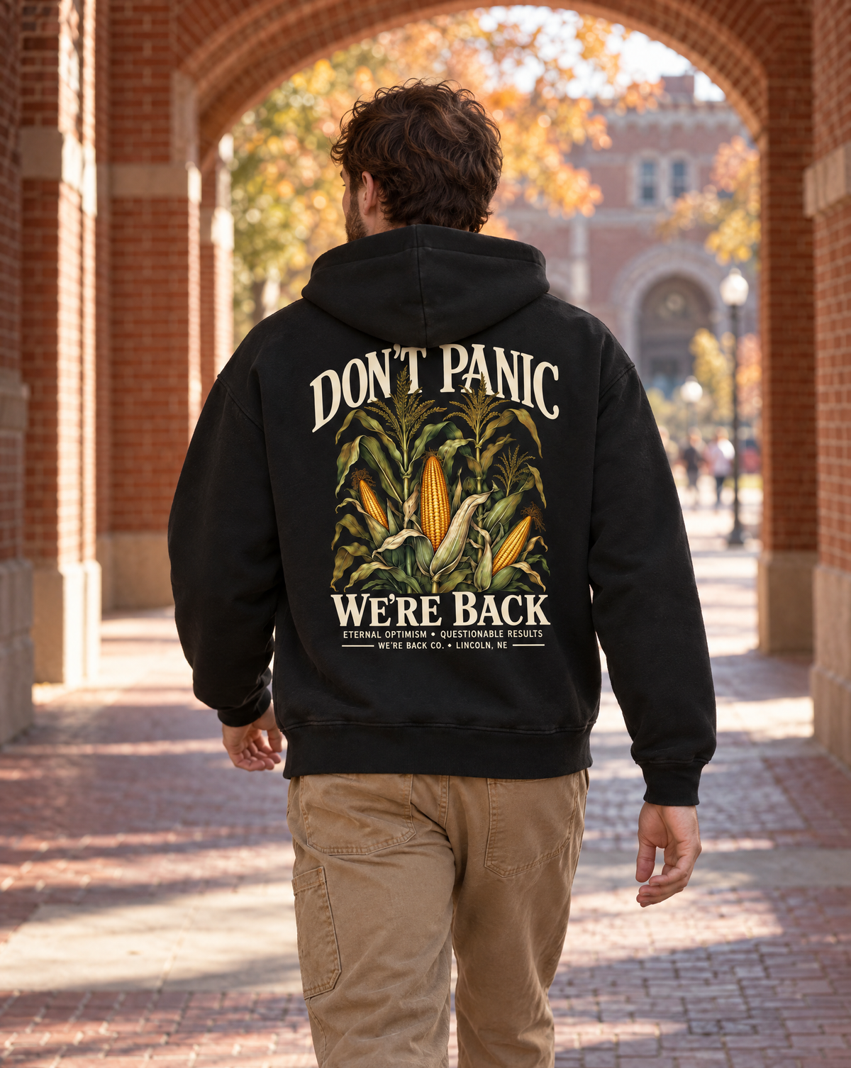 Back view of the True Black Don’t Panic Hoodie worn beneath a brick stadium arch