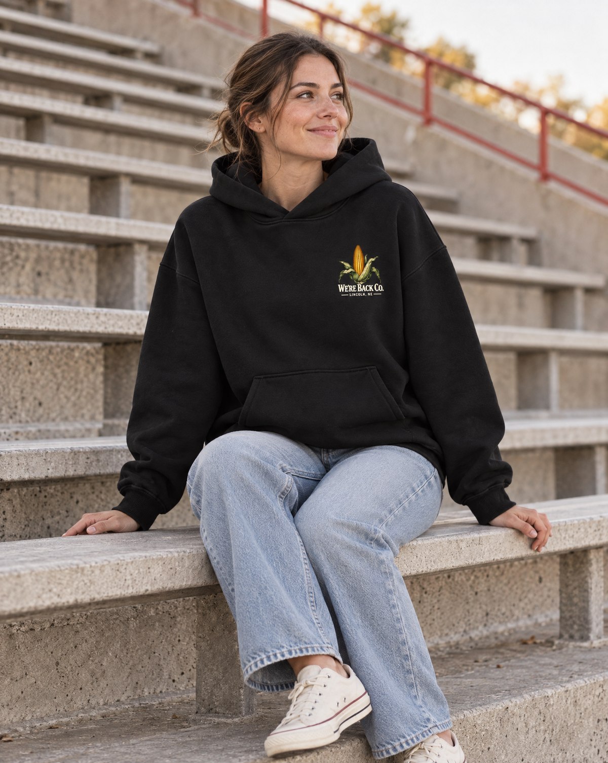 Front view of the True Black Don’t Panic Hoodie worn in concrete stadium bleachers
