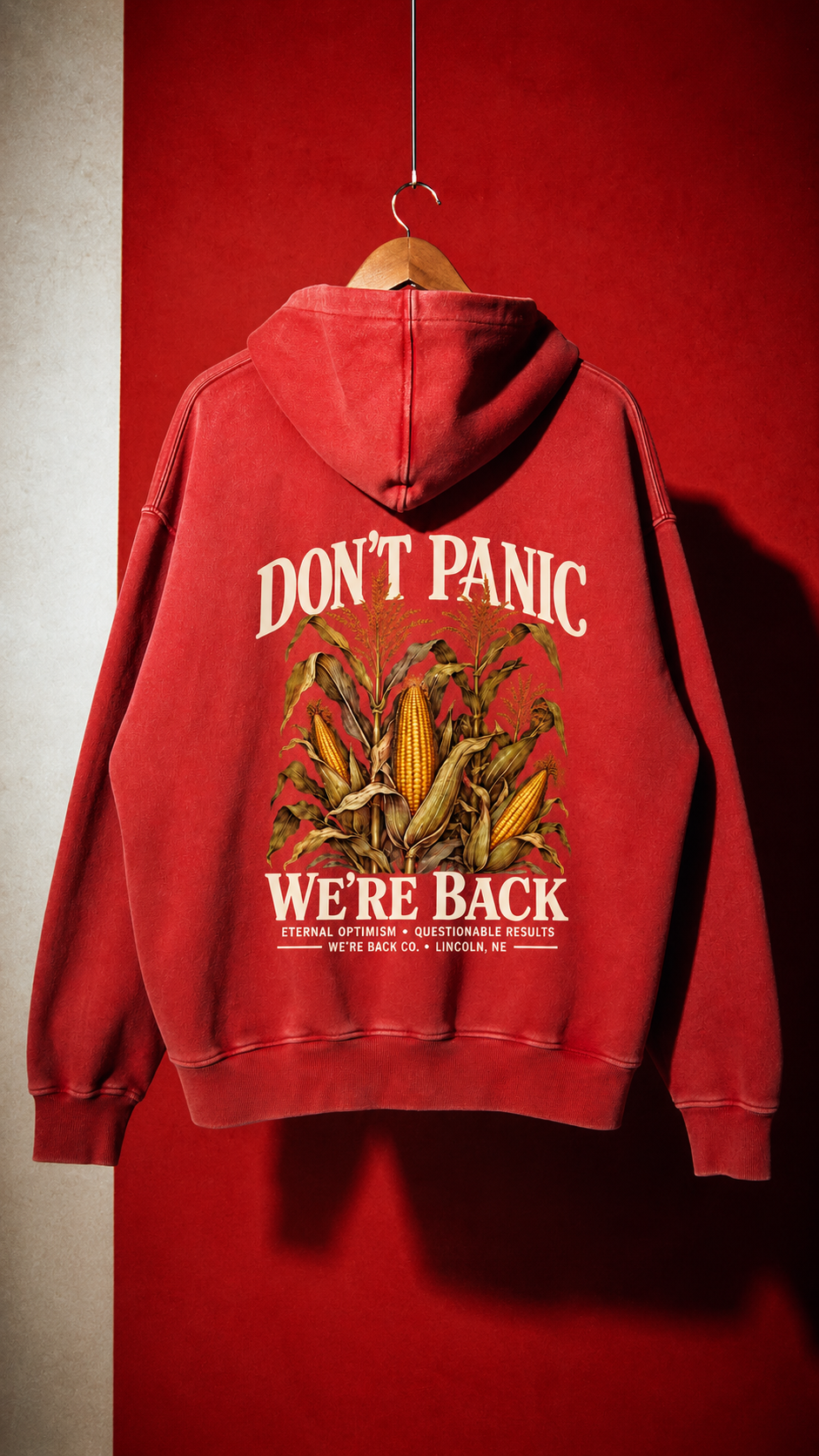 Back of the vintage red Don't Panic Hoodie hanging against a red wall.